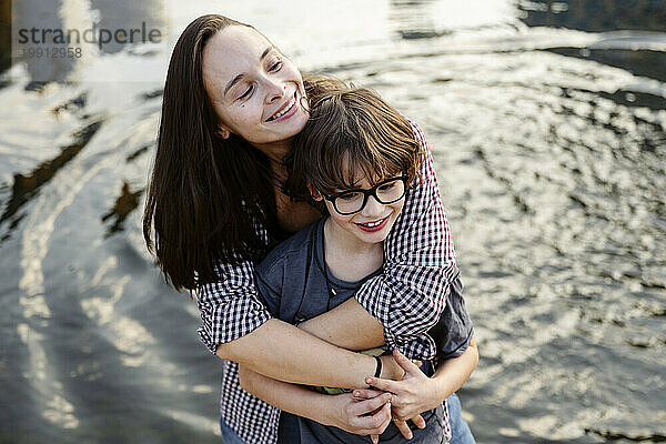 Lächelnde Mutter umarmt Sohn am See