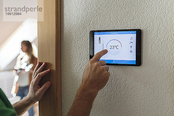 Mann passt die Temperatur über die Hausautomations-App auf dem Tablet-PC an