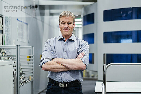 Portrait of a confident businessman at modern machine in a factory