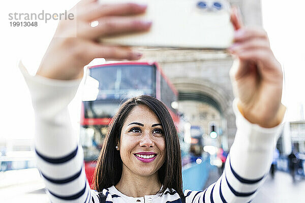 Glückliche Frau  die in der Londoner Innenstadt ein Selfie mit ihrem Smartphone macht