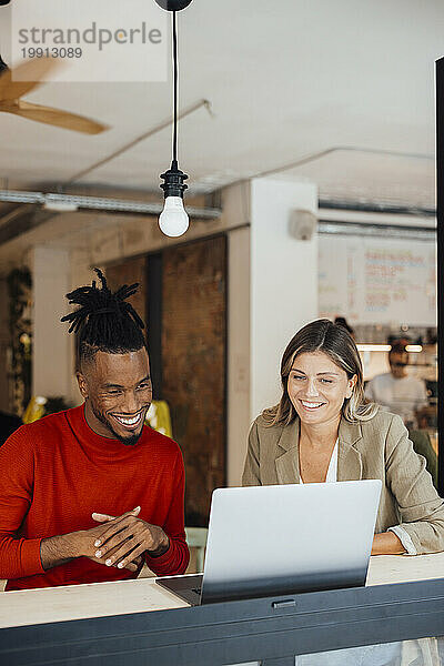 Lächelnde Geschäftskollegen planen am Laptop im Café