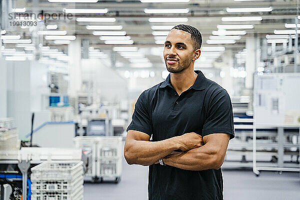 Employee standing in a factory with arms crossed