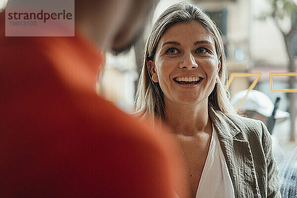 Junge lächelnde Geschäftsfrau mit Kollegen im Café