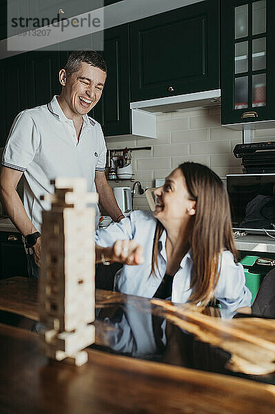 Happy couple playing block removal game in kitchen
