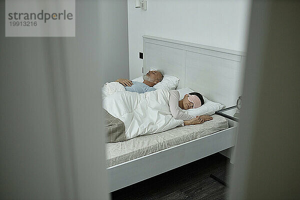 Mann und Frau schlafen im Bett im pastellfarbenen Zimmer