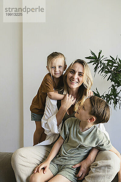 Glückliche blonde Mutter mit Söhnen im Wohnzimmer zu Hause