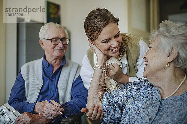 Fröhliche ältere Frau umarmt die medizinische Fachkraft zu Hause