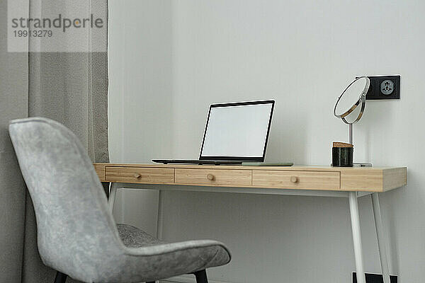 Tisch mit Laptop und Spiegel im Heimbüro