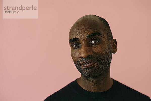 Smiling man against pink background