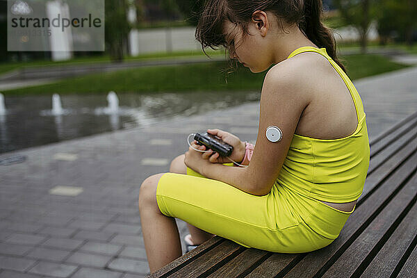 Ein Mädchen mit Diabetes misst ihren Blutzuckerspiegel an einer Insulinpumpe  die einen CGM-Sensor trägt
