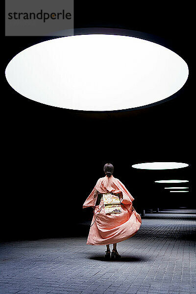 Woman wearing kimono and dancing under spotlight