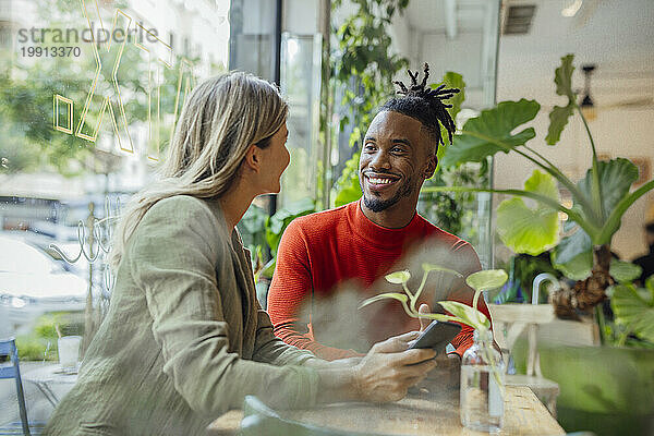 Lächelnder Geschäftsmann diskutiert mit Kollegen im Café