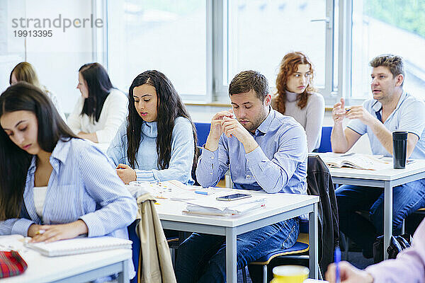 Multiethnische Studenten lernen am Schreibtisch im Klassenzimmer