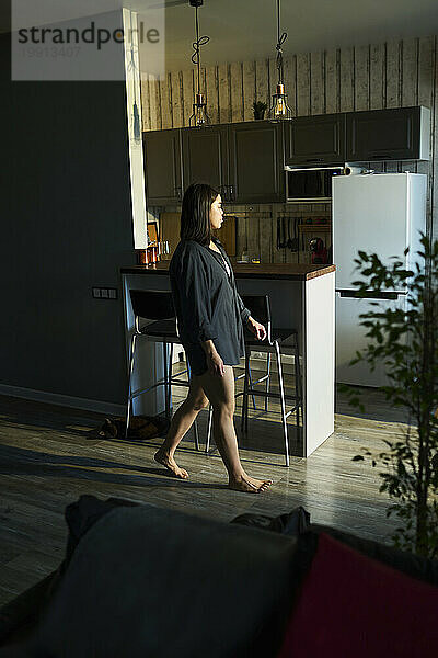 Young woman walking near kitchen at home