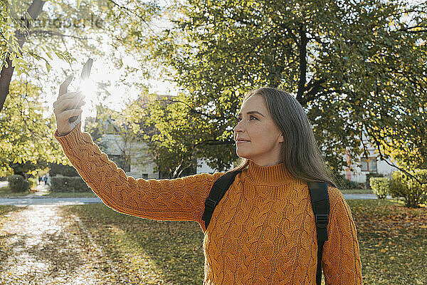 Frau macht Selfie mit Smartphone im Herbstpark