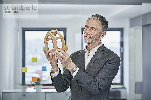 Smiling real estate agent examining model house in office