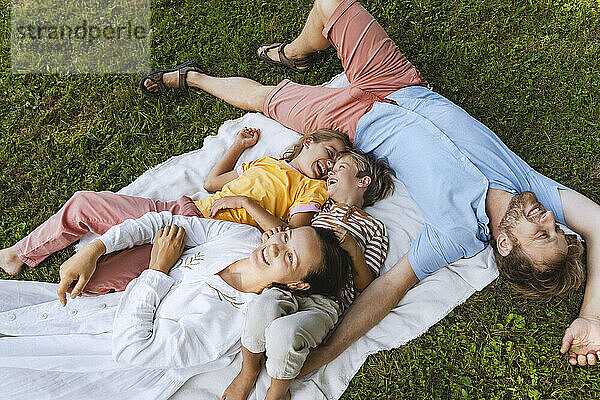 Glückliche Familie  die sich im Park auf eine Decke legt