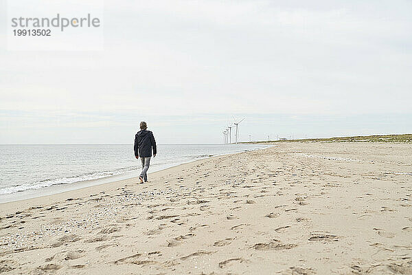 Älterer Mann spaziert an der Küste am Strand entlang