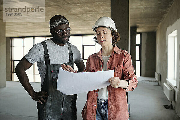 Ingenieur diskutiert mit Bauarbeiter vor Ort über Bauplan