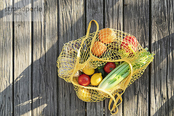 Vegetables in mesh bag lying on wooden surface