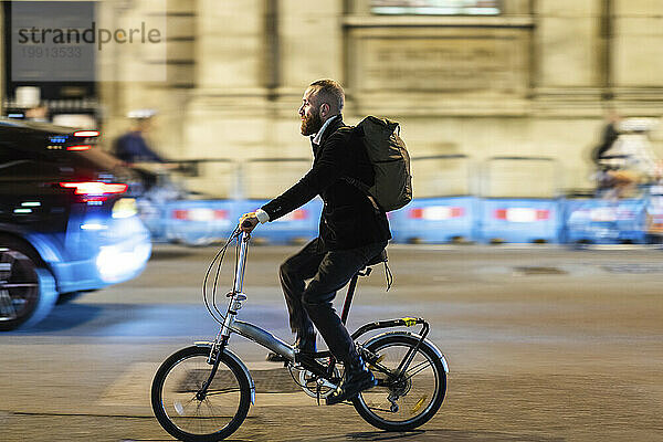 Commuter with backpack cycling on road in city