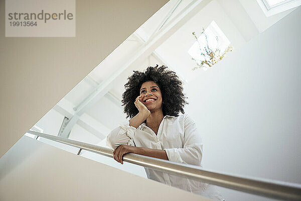 Smiling businesswoman leaning on railing at work place