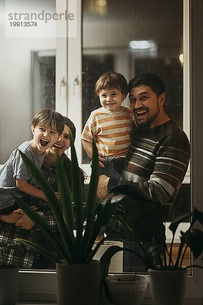 Happy family standing near window at home