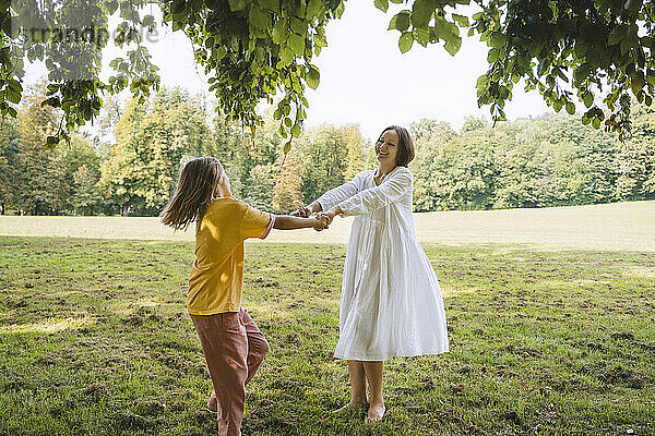 Mutter dreht Tochter  die auf Gras im Park steht