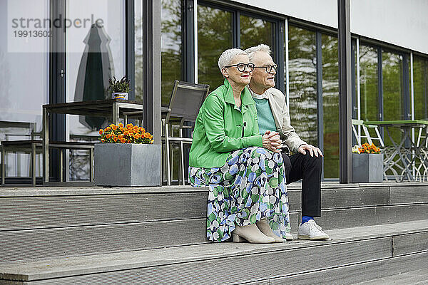Älteres Paar sitzt auf Stufen vor seinem Haus