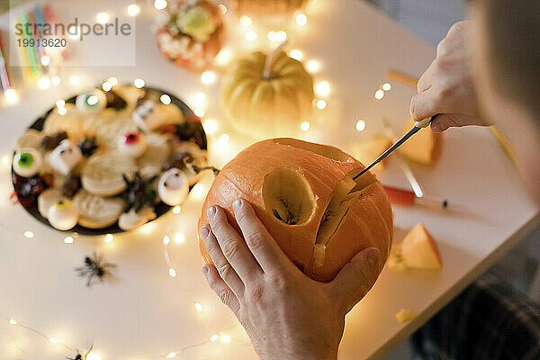 Man carving pumpkin with knife at home