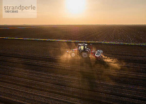 Serbia  Vojvodina Province  Aerial view of tractor sowing seeds at sunset