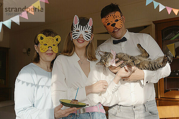 Familie trägt Tiermasken und feiert zu Hause den Geburtstag der Katze