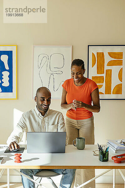 Zufriedene Kollegen schauen auf Laptop und arbeiten remote im Heimbüro