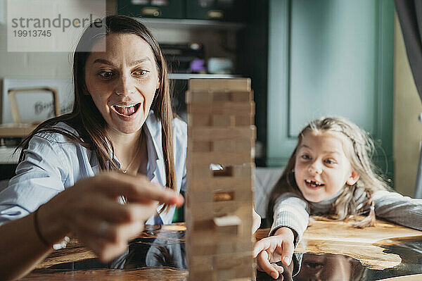 Lächelnde Mutter und Tochter spielen zu Hause Blockentfernungsspiel