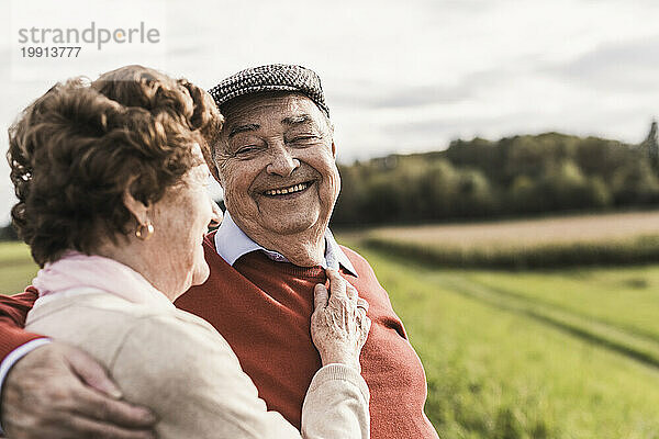 Happy senior couple spending leisure time at field on sunny day