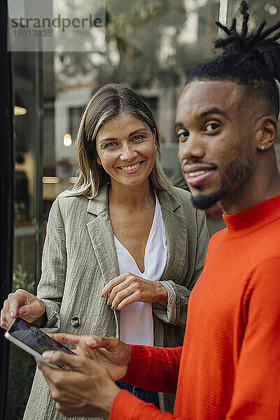 Geschäftsmann hält Tablet-PC mit Kollege in der Nähe eines Cafés