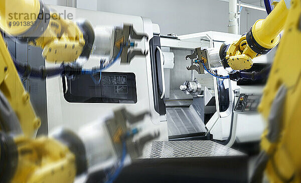 Gelbe Roboterarme mit Maschinen in der Fabrik