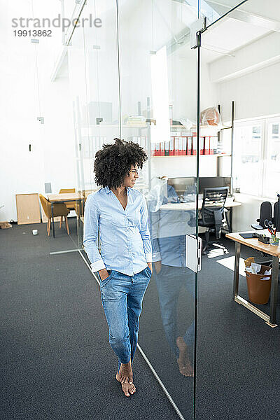 Businesswoman looking through glass wall at office