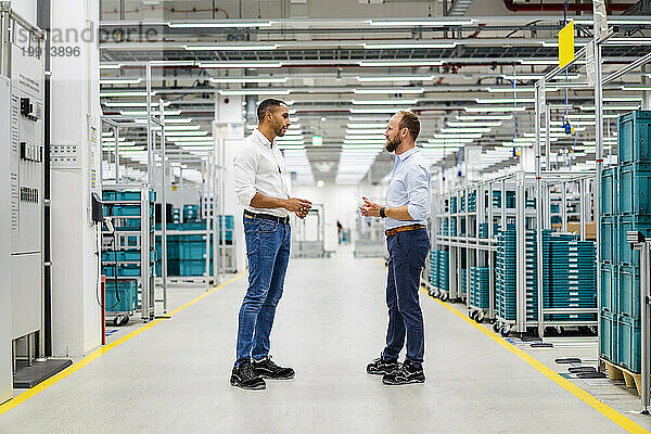Zwei Geschäftsleute stehen und reden in einer Fabrik