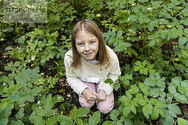 Smiling girl crouching amidst plants