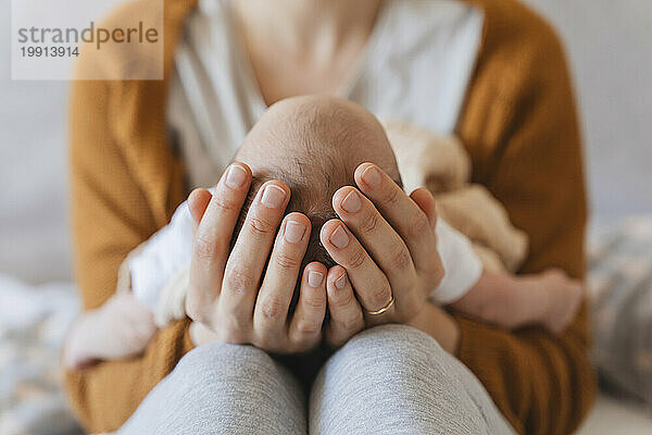 Mutter hält neugeborenen Sohn zu Hause in den Händen