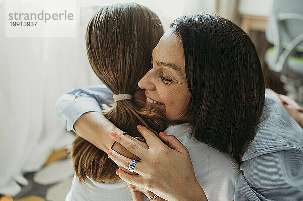 Happy mother hugging daughter at home