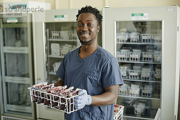 Lächelnder Labortechniker mit Blutbeuteln