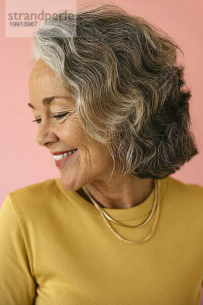 Lächelnde ältere Frau vor rosa Hintergrund