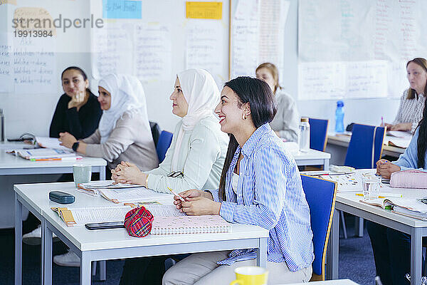 Multiethnische Schüler sitzen an Schreibtischen und lernen gemeinsam im Klassenzimmer