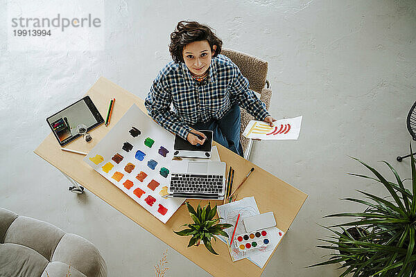 Lächelnder Designillustrator mit Laptop am Schreibtisch im Büro