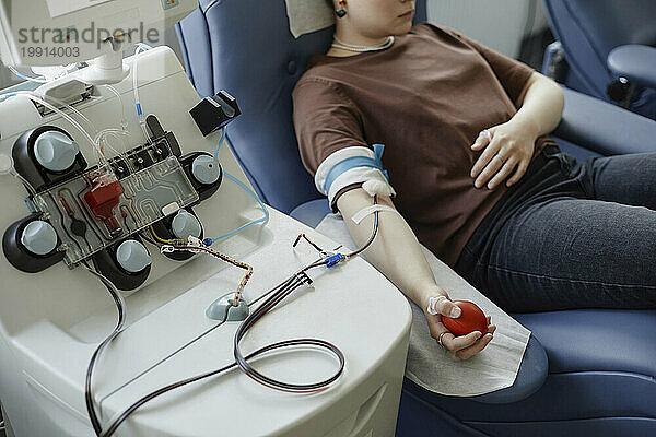 Young woman lying on couch with ball in hand at blood donation center