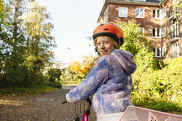 Lächelndes Mädchen  das mit dem Fahrrad im Park über die Schulter schaut