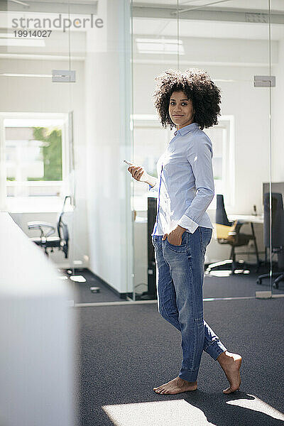 Businesswoman with hand in pocket standing at work place