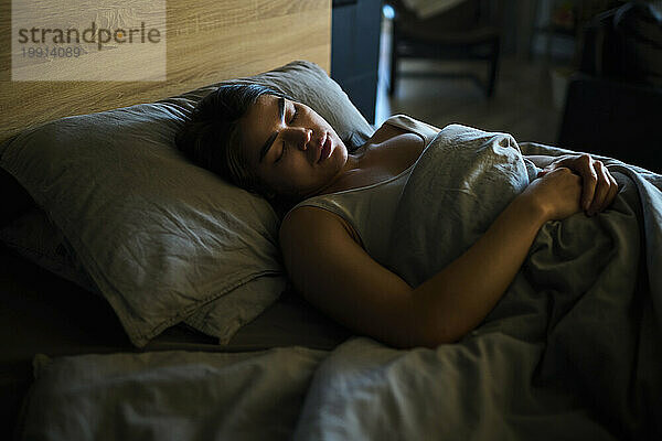 Young woman sleeping on bed at home